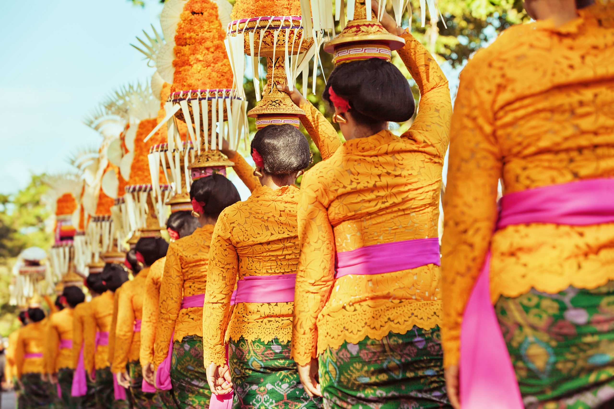  A group of women in traditional Javanese dress carrying offerings on their heads during a religious ceremony.